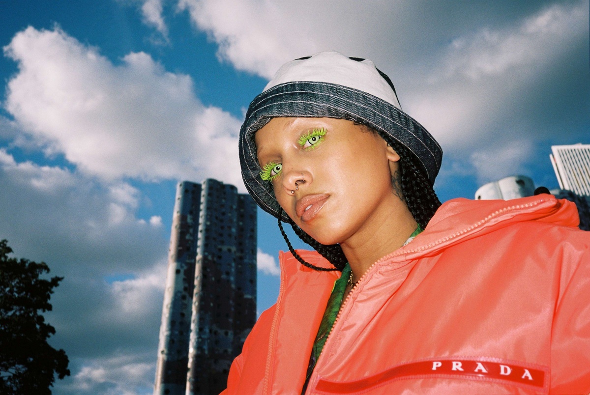 A woman looks down at the camera with electric green eyelashes