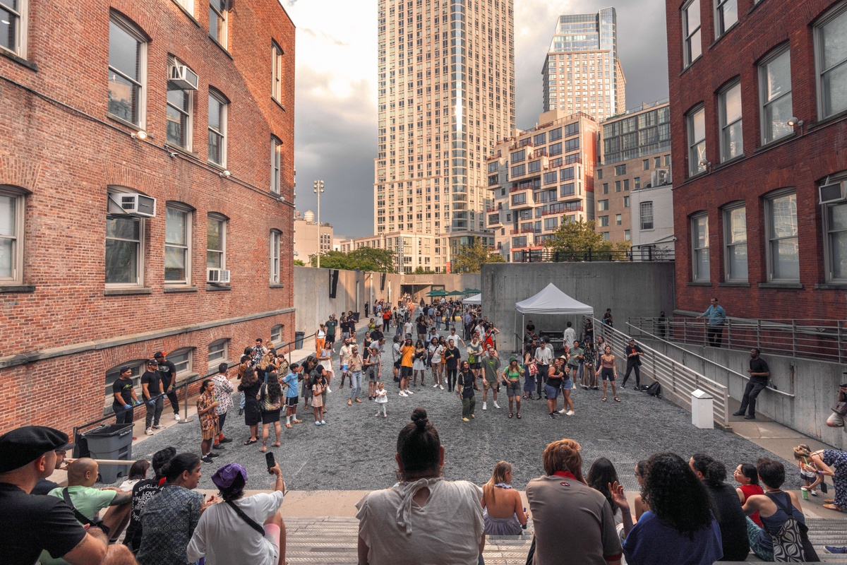 People sitting on the steps of PS1, looking out onto the Courtyard