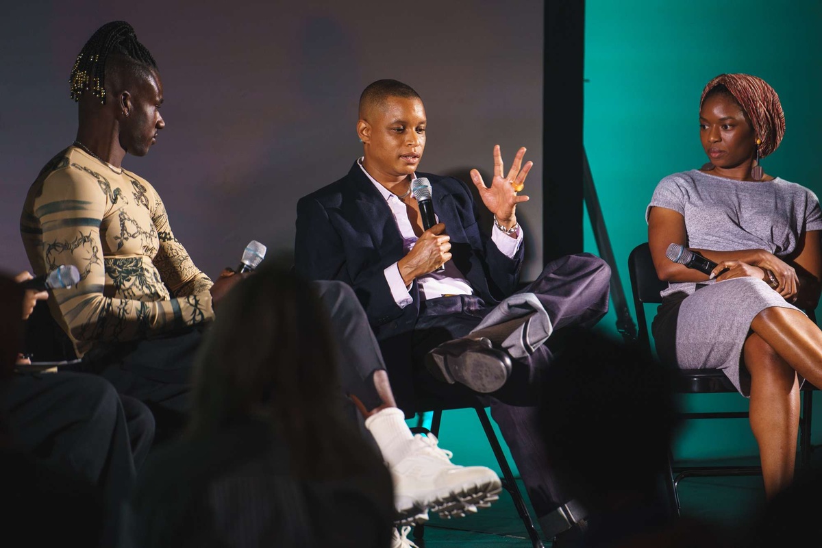 Three artists sit on a stage in conversation.