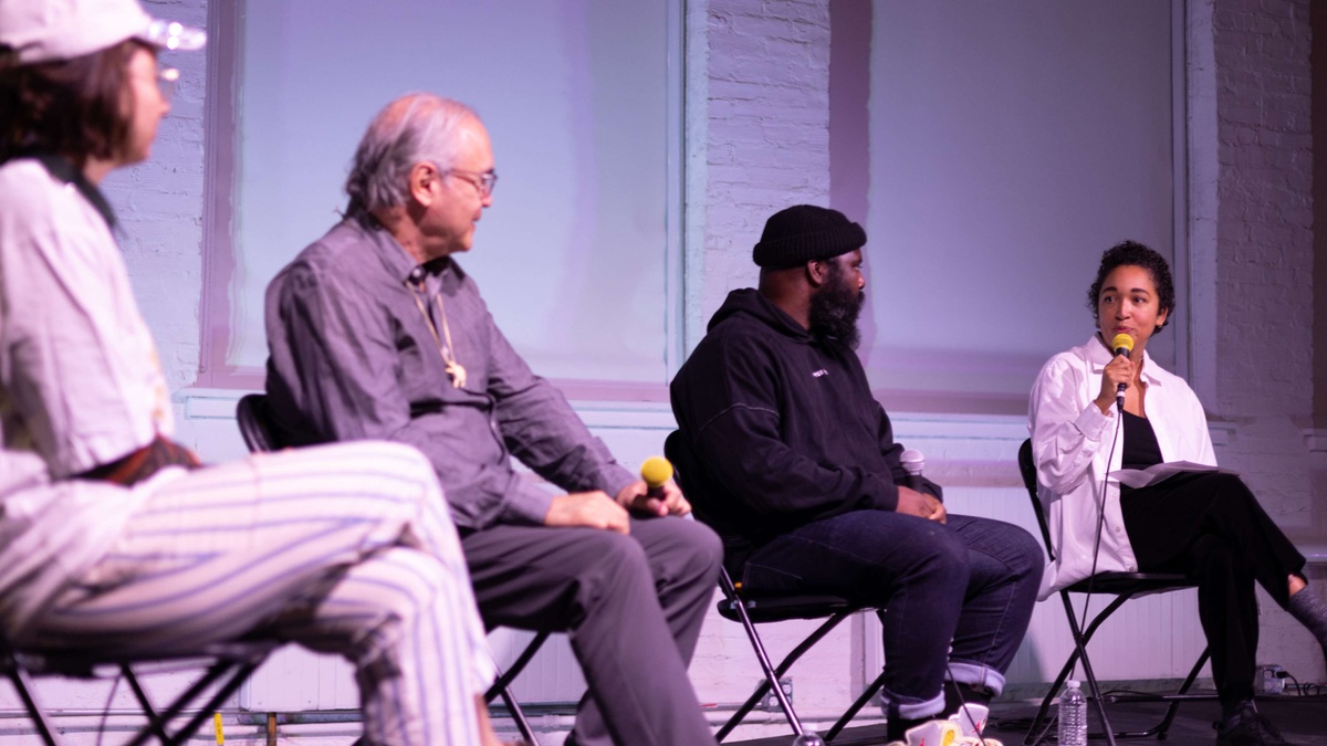 four people in discussion, seated on a stage