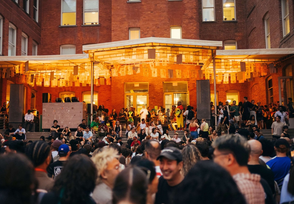 Warm Up crowd dancing against a DJ booth at MoMA PS1
