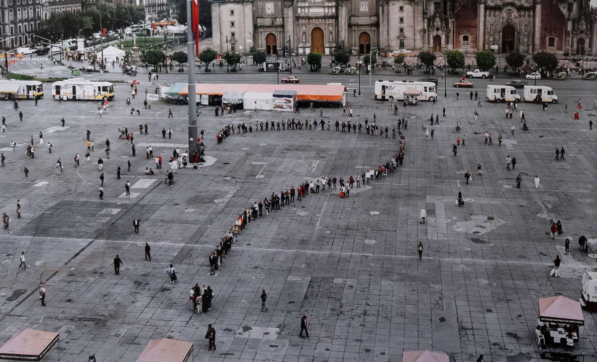 A crowd of people line up in the shape of a question mark, forming an artwork by Rirkrit Tiravanija in the Zocalo square of Mexico City.