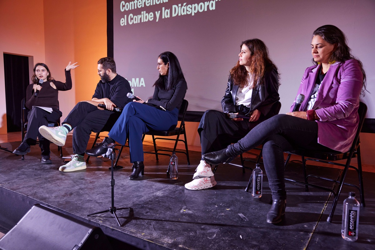 Five people sit on a stage in a panel conversation.