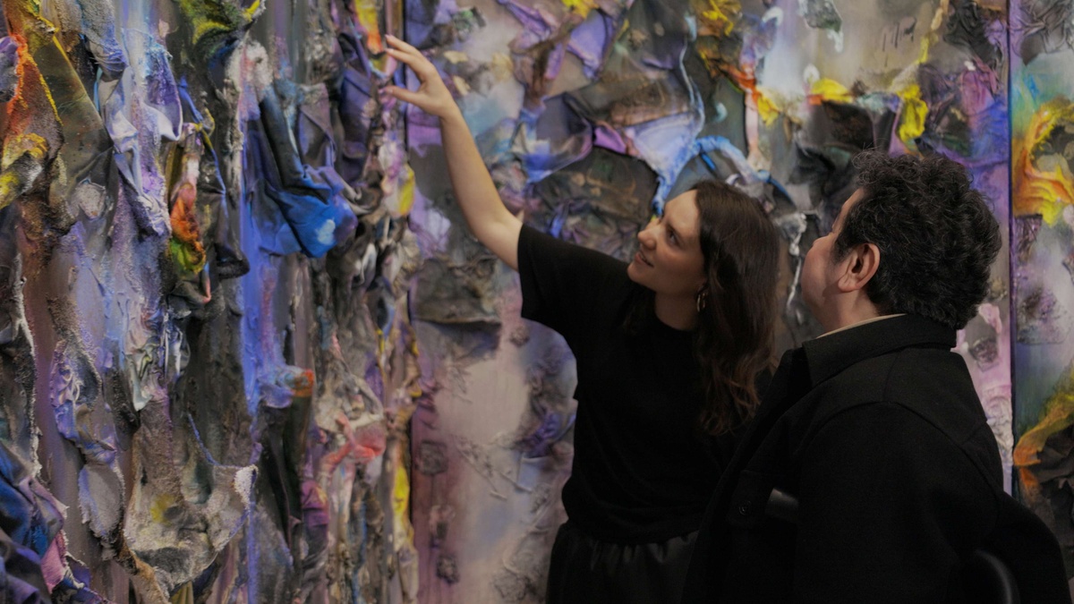 Artist Leslie Martinez and Curator Elena Ketelsen Gonzalez in front of a large, colorful painting by Martinez.