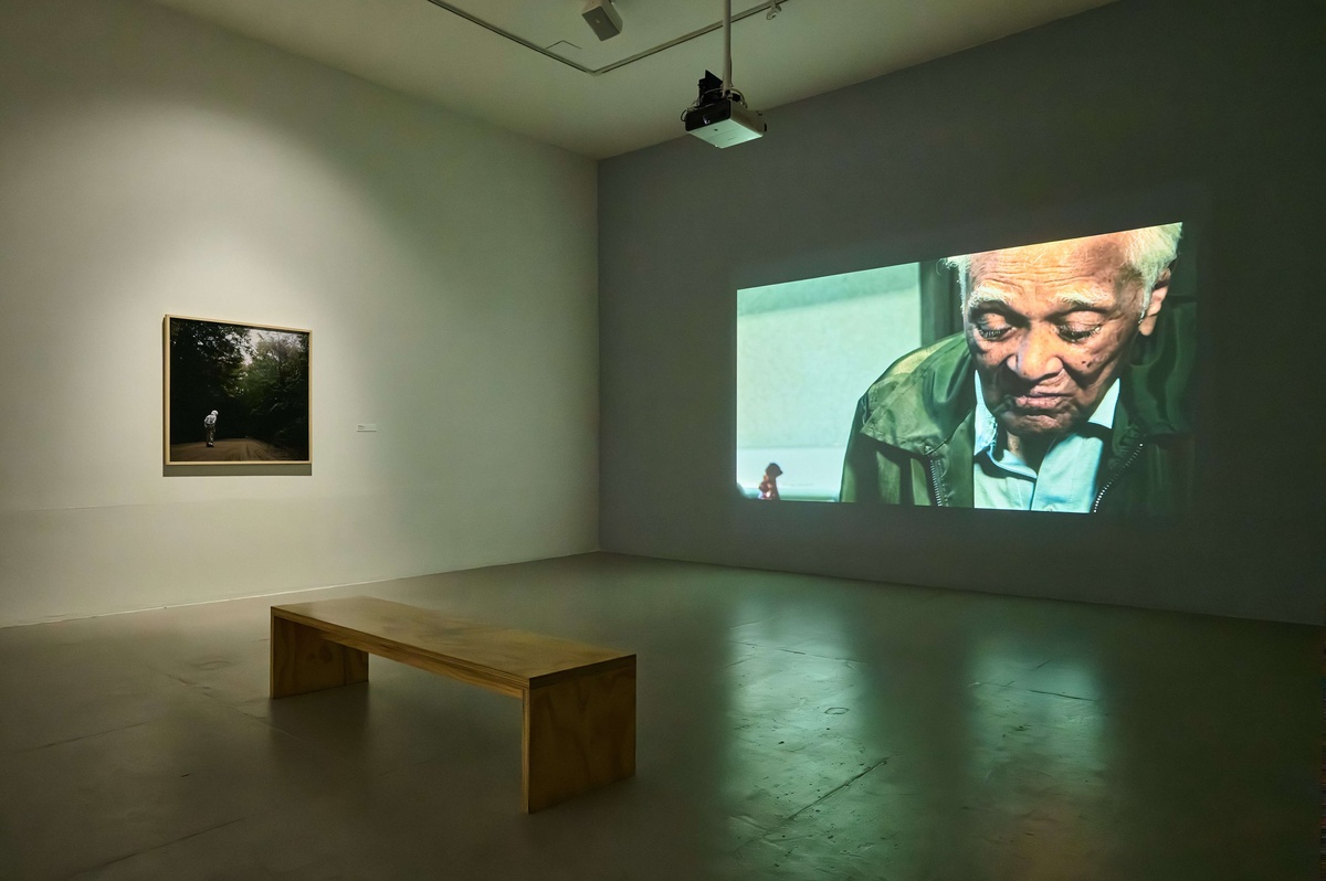 From left: A photograph hangs on a wall, flanked by a projection of a film.