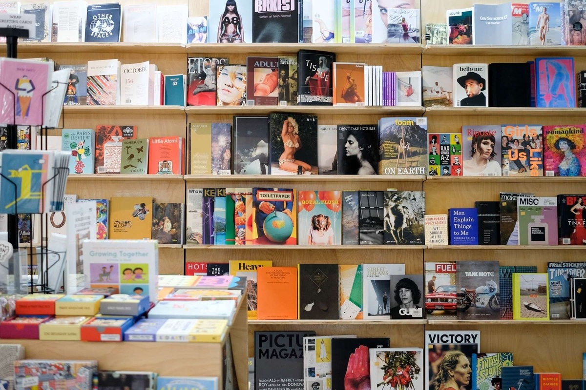 A variety of brightly colored publications line wooden shelves.