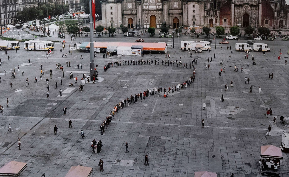 A crowd of people line up in the shape of a question mark, forming an artwork by Rirkrit Tiravanija in the Zocalo square of Mexico City.