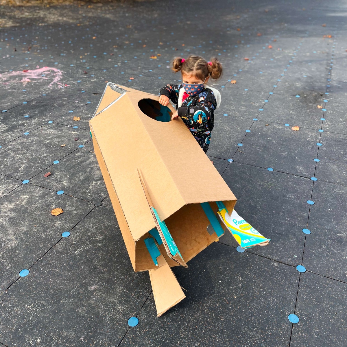 A child holds a cardboard spaceship.