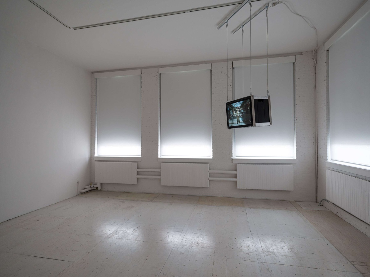 A television is suspended in the corner of an all white room.