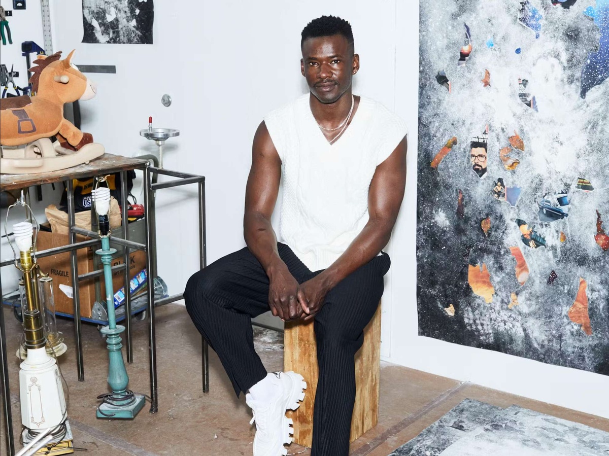 Jeffrey Meris sits on a stool in his studio