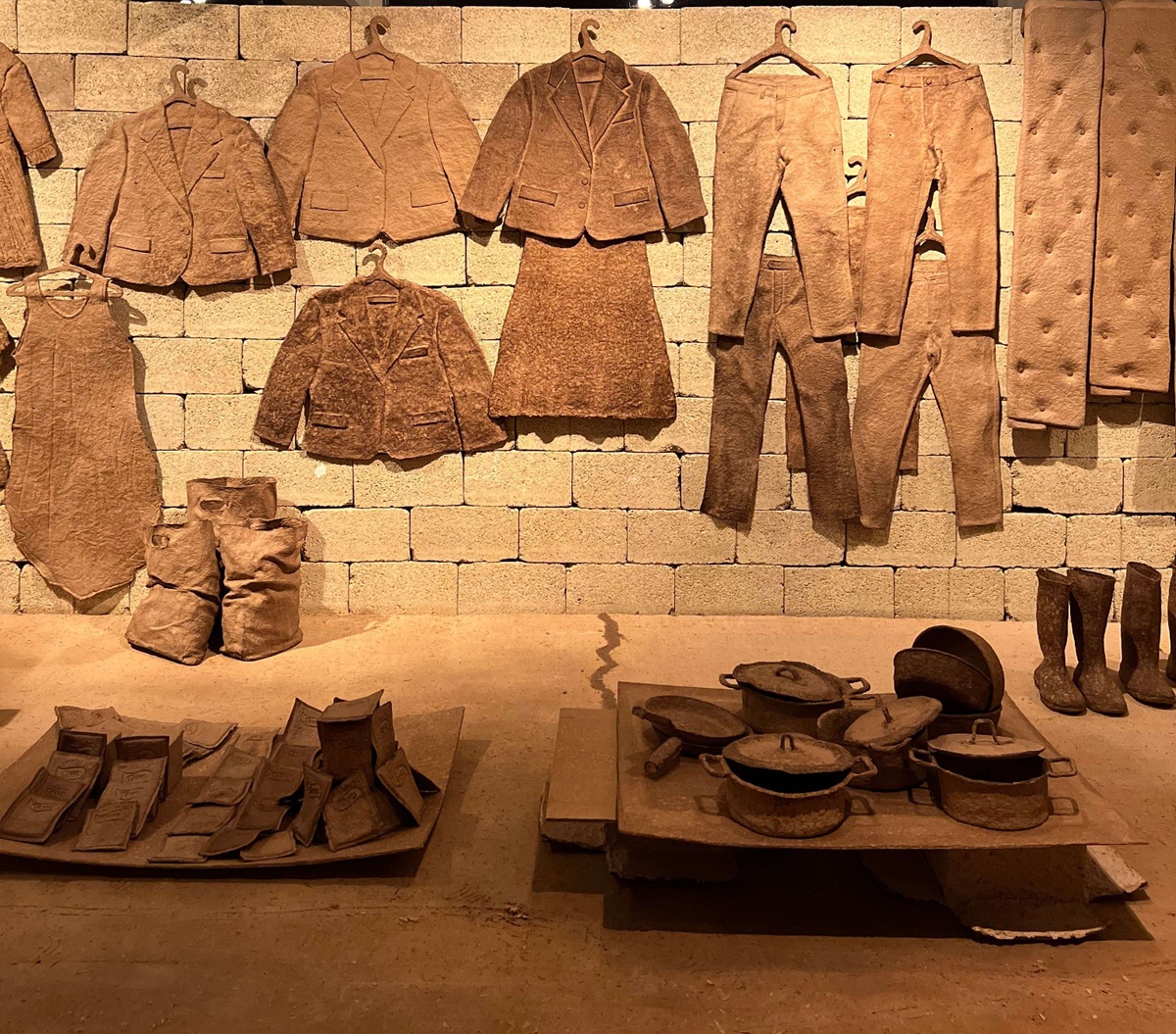 Brown clothing items are on hangers above brown pots and pans.