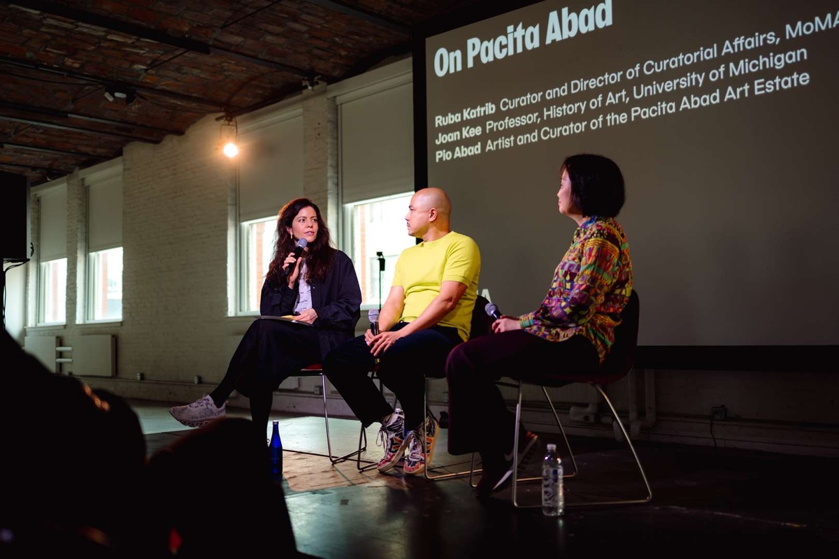 Three people sit on a stage at MoMA PS1 delivering a panel about Pacita Abad.
